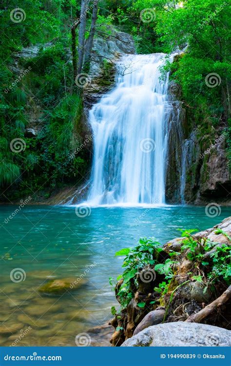 A Large Beautiful Waterfall In A Forest With Blue Water And A Trees