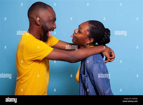 Playful Lovers Hugging And Sticking Tongue Out At Each Other