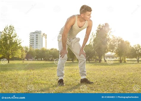 Full Length Of Tired Young Man Standing In Park After Jogging Stock