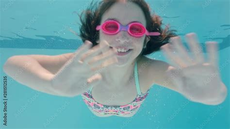 Happy Girl Swimming Underwater In Pool Smiling Waving Hand Enjoying