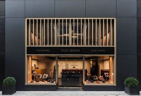 The Store Front Of A Shoe Shop With Glass Doors And Wooden Railings On