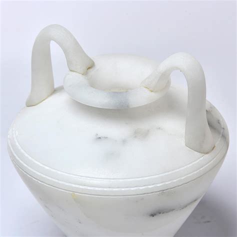 Crafted of alabaster with a cotton designed to highlight the classic elegance and timeless allure of white marble, this alabaster table. New White Alabaster Vase with Handles For Sale at 1stdibs