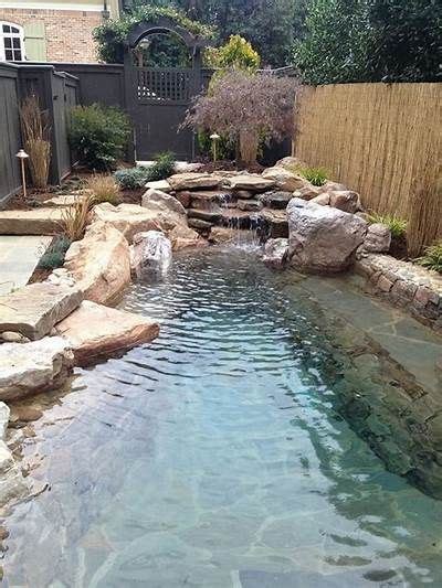 A Small Pool In The Middle Of A Backyard With Rocks Around It And A