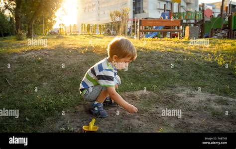 Photo Of 3 Years Old Little Boy Sitting On The Ground At Park And