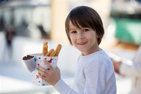 Kid Eating Churros Sweet Fried Custard Dough Pastry In Bag With