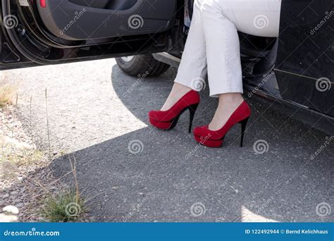 Woman Gets Out Of The Car Legs With Red High Heeled Shoes Stock Photo