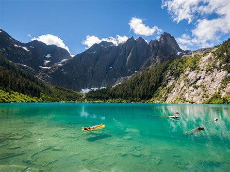 Two People In Kayaks Floating On The Water Near Mountains