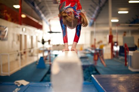 Young Gymnast Doing Handstand On Balance Beam Stock Photo Download