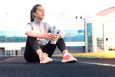 Beautiful Young Woman In Sports Clothing Drinking Water After Sport