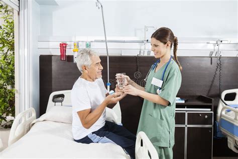 Paciente Que Recibe El Vidrio De La Medicina Y De Agua De Enfermera De