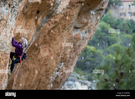 Side View Of Single Adventurous Woman Rock Climbing Up Cliff Siurana