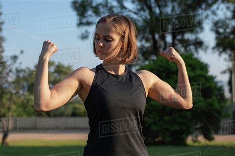 Confident Muscular Woman Flexing Muscles While Standing In Park Stock