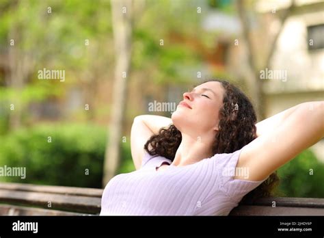 Relaxed Woman Resting With Arms On Head Sitting In A Bench In A Park