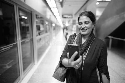 Happy Mature Indian Woman Using Phone While Exploring The City Stock