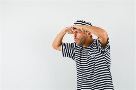 Free Photo Young Man Looking Far Away With Hand Over Head In Striped