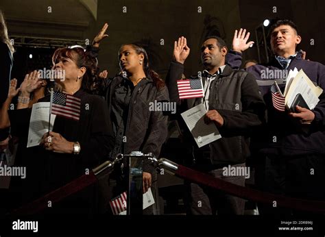 naturalization candidates raise their hands and pledge the oath of allegiance during a ceremony
