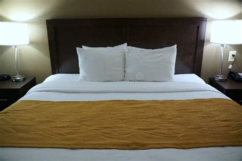A Comfortable Bed With White Pillows Bed Sheet And Mustard Blanket