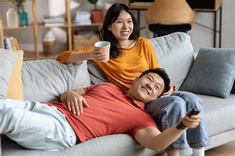 Relaxed Chinese Lovers Resting Together At Home Watching Tv Stock