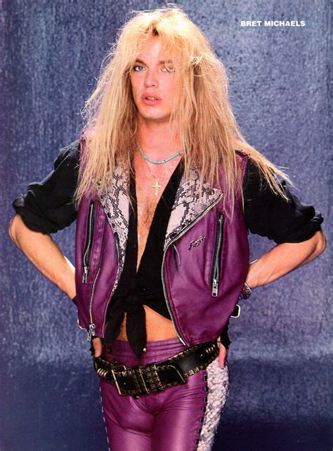 a man with long blonde hair wearing purple leather pants and a black shirt is standing in front