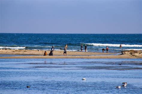 People Walking And Sitting On On The Silky Brown Sand At The Beach
