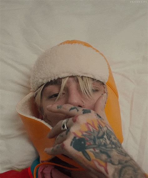 A Man With Tattoos Covers His Face While Laying In Bed
