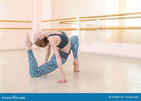 Very Flexible Caucasian Woman Doing Stretching Exercises In Dance Class With Mirrors And Barre