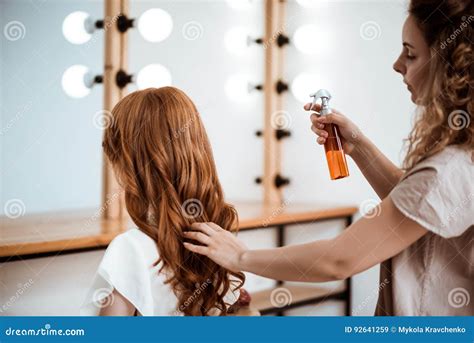 female hairdresser making hairstyle to redhead girl in beauty salon stock image image of