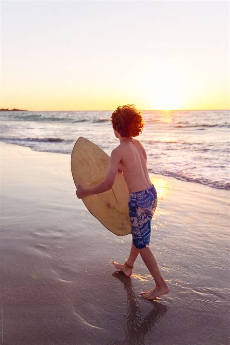 Boy Viewed From Behind About To Launch Himself Off Onto A Skim Board