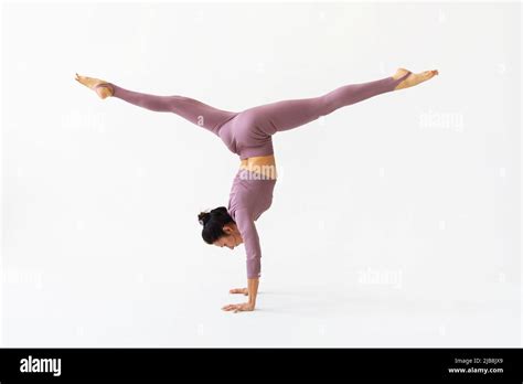 A Woman Practicing Yoga Performs The Adho Mukha Vrikshasana Exercise