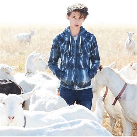 A Young Man Standing In Front Of A Herd Of Goats