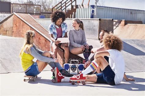 Friends In Roller Skates And On Skateboard Using Digital Tablet At