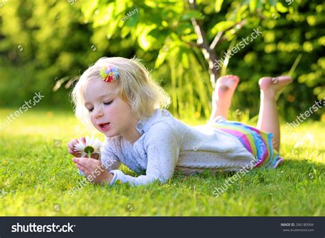 Little Happy Child Smiling Blonde Toddler Girl Lying On Green Grass