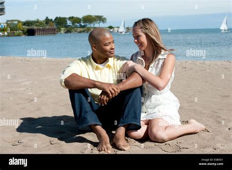 Ein Glückliches Interracial Paar Sitzt Am Strand An Einem Sonnigen Tag