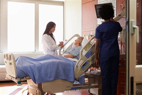 Female Doctor Talks To Senior Female Patient In Hospital Bed Stock Image Everypixel