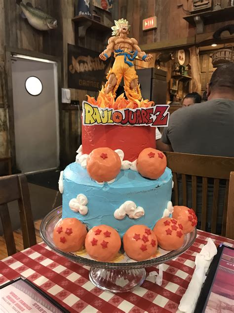 A Dragon Ball Themed Cake Sits On A Table In Front Of A Person Sitting