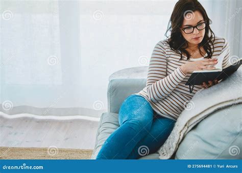 To Read Is To Relax A Young Woman Relaxing On The Sofa And Reading A Book At Home Stock Image