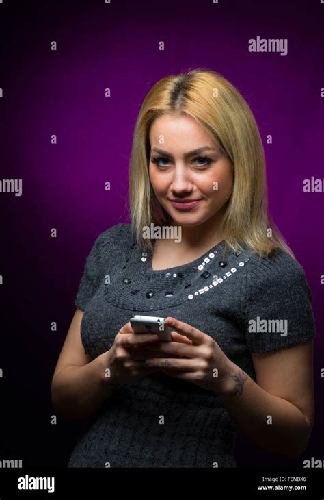 Happy Blond Haired Model Holding A Smartphone On Black Background Stock