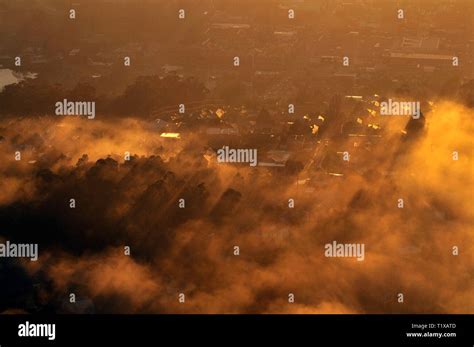Aerial Image Of Orange Dawn Sunlight Shining Through River Ground Mist