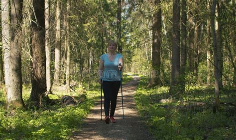 Mature Woman With Trekking Poles Walking In The Forest Stock Image
