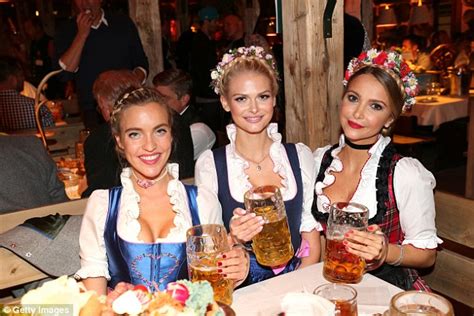 a group of three girls smile as they hold up their large glasses of beer at last year s celebration
