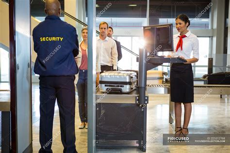 Airport Security Guard With Passengers Walking Through Body Scanner At Airport Terminal — Travel