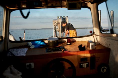 Independent Fisherman Operating Winch At Boats Bow Stock Photo