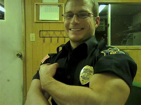 A Man In A Police Uniform Is Posing For The Camera While Holding His