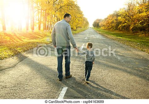 happy father and son walk in nature walk on a road canstock