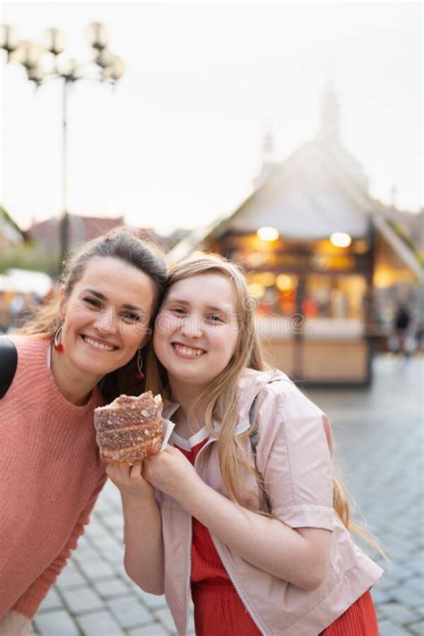 Smiling Mother And Daughter At Fair In City Eating Trdelnik Stock Photo