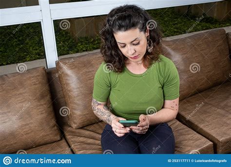 Brazilian Tattooed Woman Sitting On The Sofa And Interacting With Her