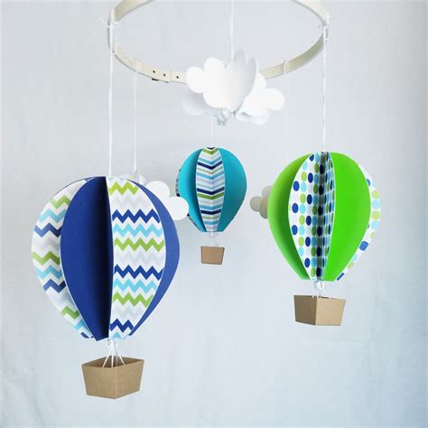 Three Colorful Hot Air Balloons Hanging From Strings On A White Wall With Clouds In The Background