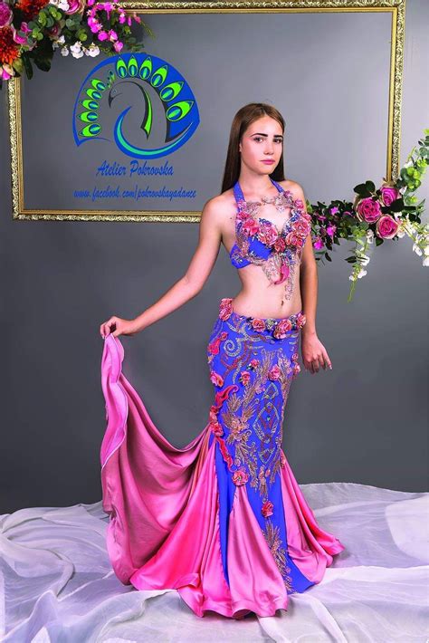 A Woman In A Pink And Blue Belly Dance Outfit With Flowers Around Her Waist Posing For The Camera