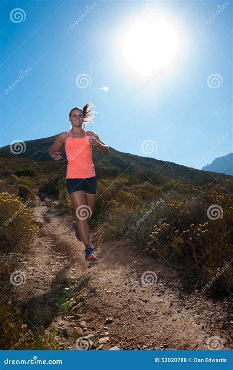 Blonde Female Trail Runner Running Through A Mountain Landscape Stock