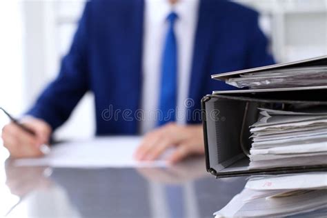 Binders With Papers Are Waiting To Be Processed With Businessman Back